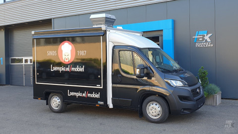 Zijaanzicht van een verkoopwagen voor loempia's met gesloten luifel
