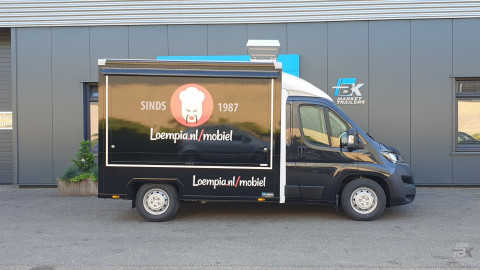 Zijaanzicht van een verkoopwagen voor loempia's met gesloten luifel