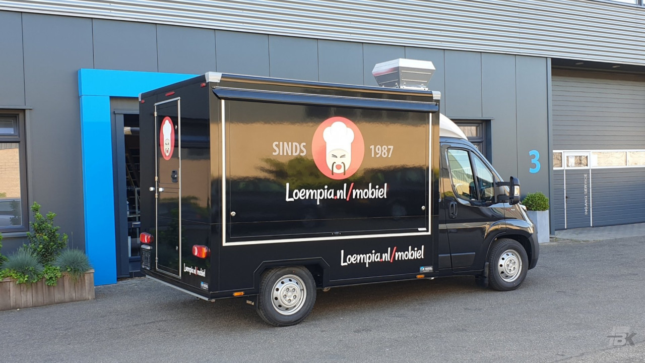 Zijaanzicht van een verkoopwagen voor loempia's met gesloten luifel