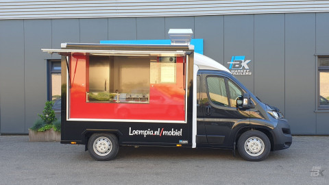 Zijaanzicht van een verkoopwagen voor loempia's met geopende luifel