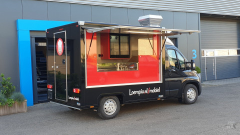 Zijaanzicht van een verkoopwagen voor loempia's met geopende luifel