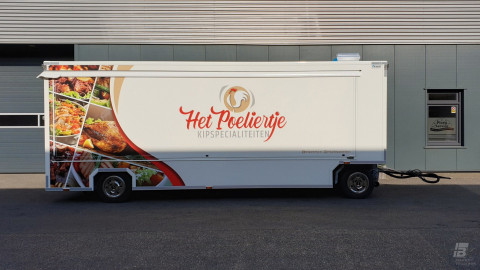 Zijaanzicht van een aanhangwagen voor kipspecialiteiten met gesloten luifel