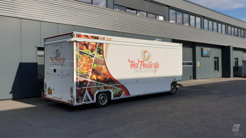 Zijaanzicht van een aanhangwagen voor kipspecialiteiten met gesloten luifel