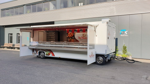 Zijaanzicht van een aanhangwagen voor kipspecialiteiten met geopende luifel en zijborden