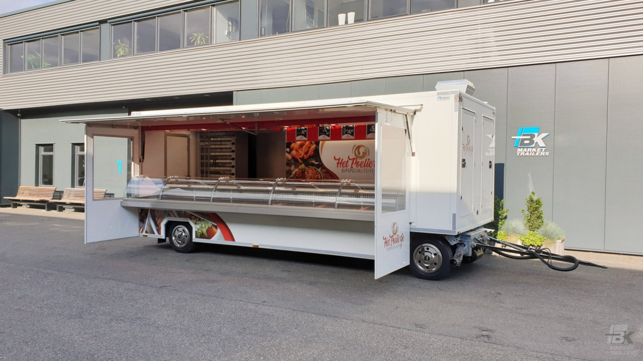 Zijaanzicht van een aanhangwagen voor kipspecialiteiten met geopende luifel en zijborden
