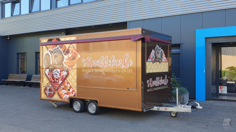 Zijaanzicht van een aanhangwagen voor wafels, pannenkoeken en ijs met gesloten luifel