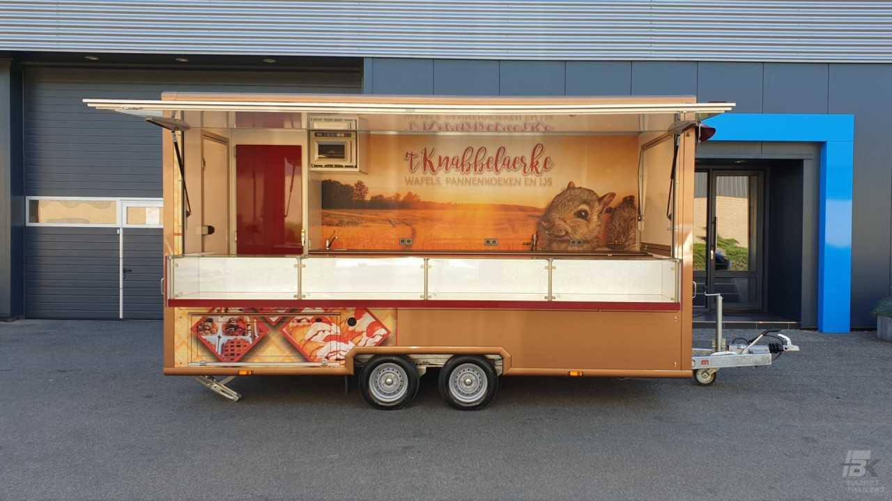 Zijaanzicht van een aanhangwagen voor wafels, pannenkoeken en ijs met geopende luifel