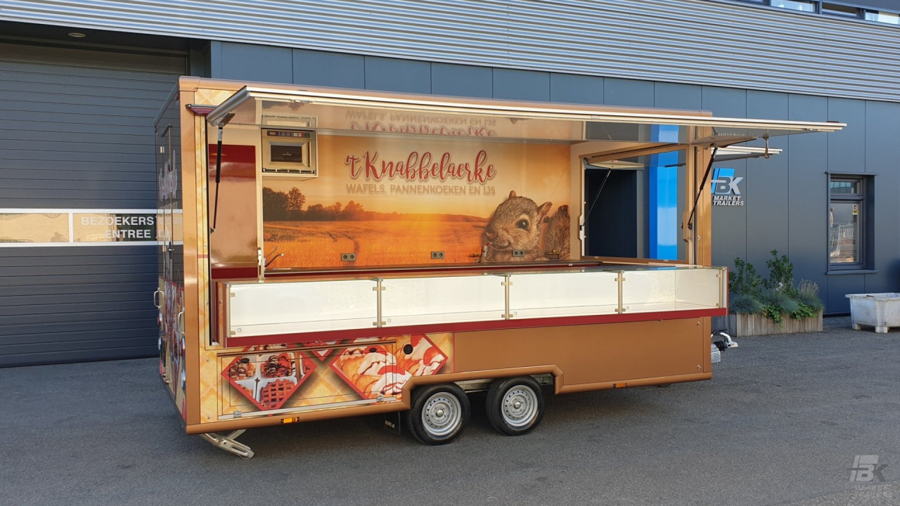 Zijaanzicht van een aanhangwagen voor wafels, pannenkoeken en ijs met geopende luifel