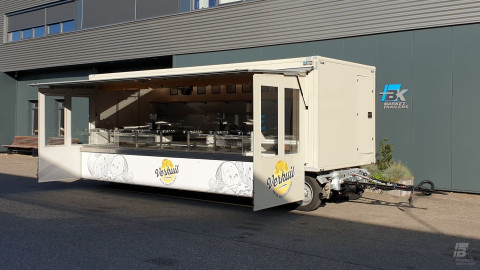 Zijaanzicht van een aanhangwagen voor kaas met geopende luifel en zijborden