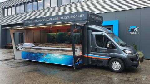 Zijaanzicht van een verkoopwagen voor vis met geopende luifel en zijborden