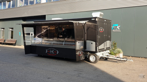 Zijaanzicht van een aanhangwagen voor vis met geopende luifel en zijborden