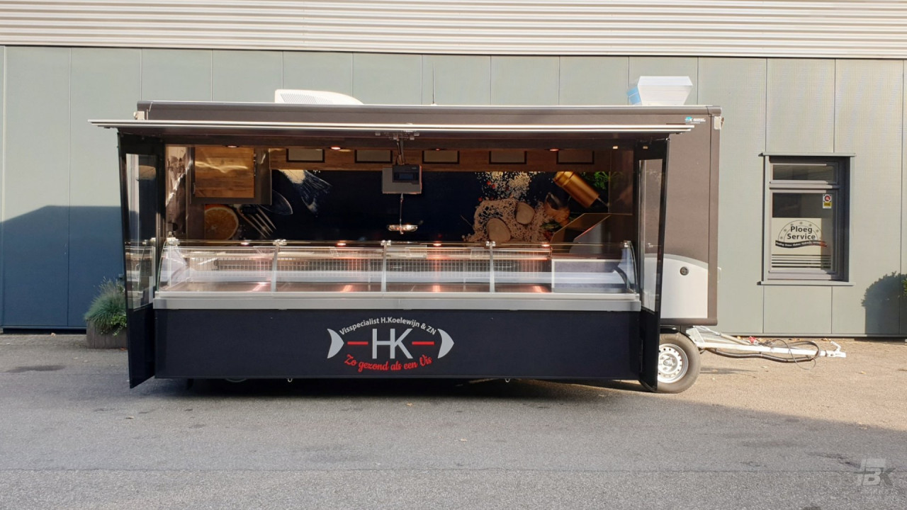 Zijaanzicht van een aanhangwagen voor vis met geopende luifel en zijborden
