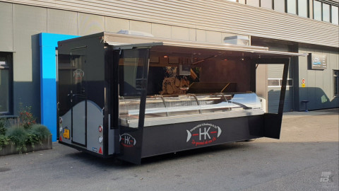 Zijaanzicht van een aanhangwagen voor vis met geopende luifel en zijborden