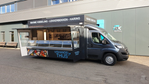 Zijaanzicht van een verkoopwagen voor vis met geopende luifel en zijborden