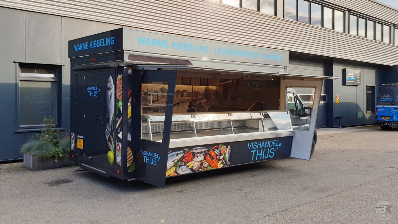 Zijaanzicht van een verkoopwagen voor vis met geopende luifel en zijborden