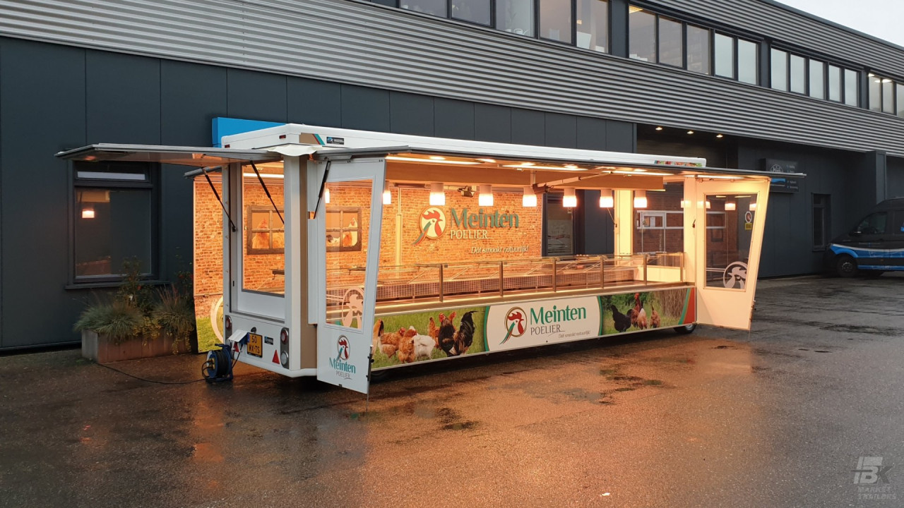 Zijaanzicht van een smalle aanhangwagen voor kip met geopende luifel en zijborden