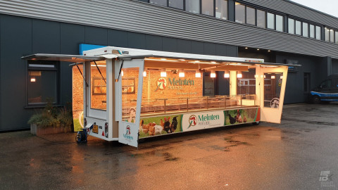Zijaanzicht van een smalle aanhangwagen voor kip met geopende luifel en zijborden