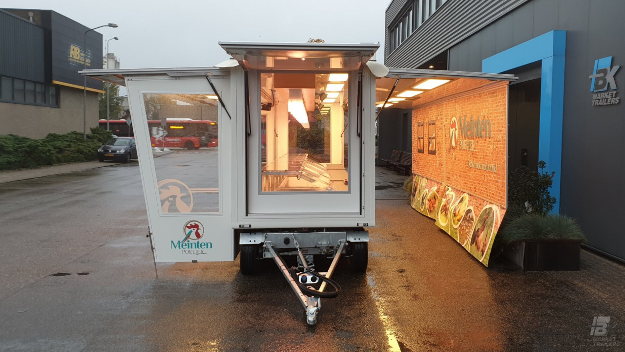 Vooraanzicht van een smalle aanhangwagen voor kip met geopende luifel en zijborden