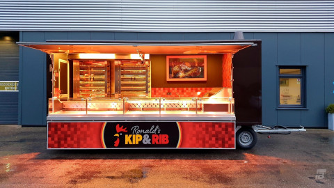 Zijaanzicht van een aanhangwagen voor kip aan het spit met geopende luifel