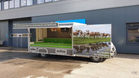 Zijaanzicht van een verkoopwagen voor kaas met geopende luifel en zijbord