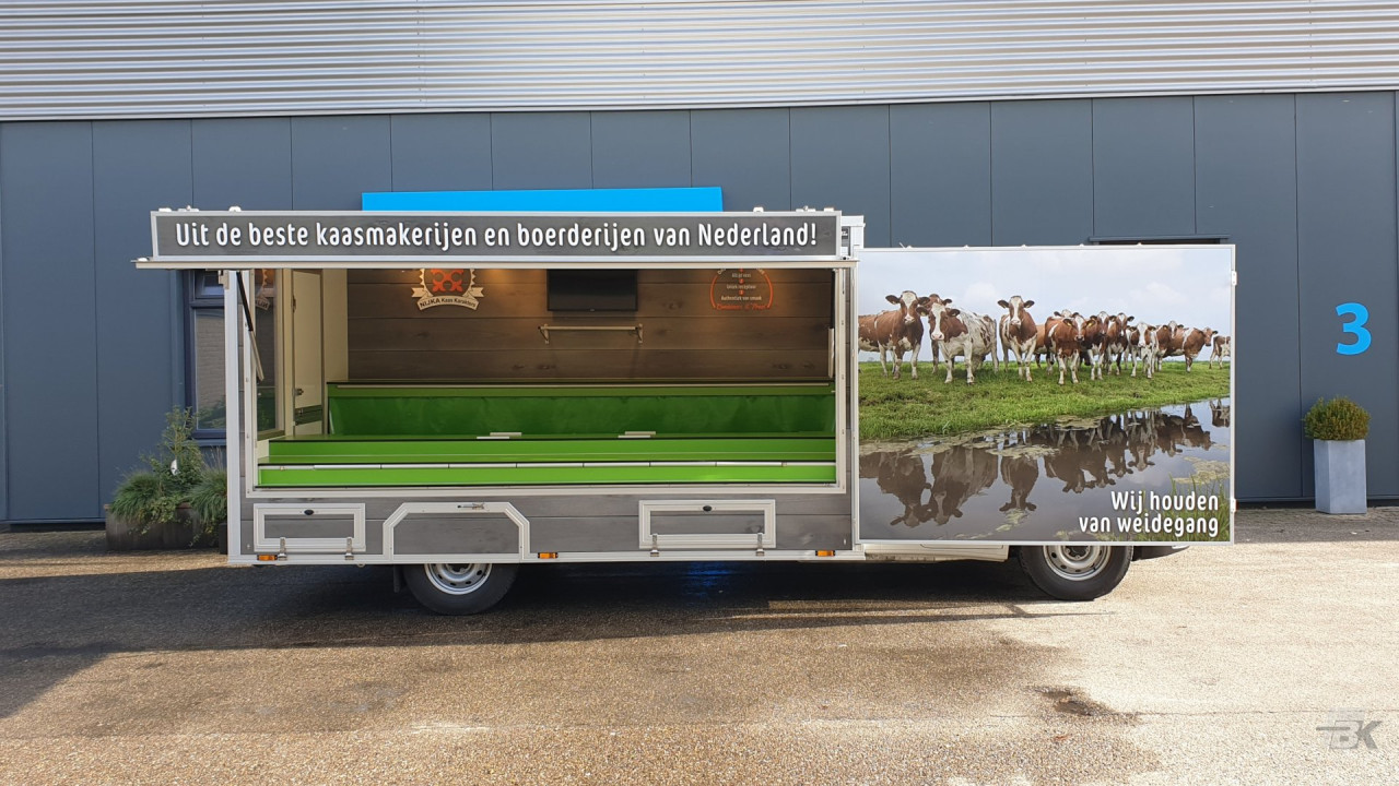 Zijaanzicht van een verkoopwagen voor kaas met geopende luifel en zijbord