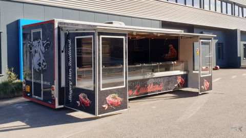 Zijaanzicht van een aanhangwagen voor vlees met geopende luifel en tochtborden