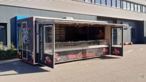 Zijaanzicht van een aanhangwagen voor vlees met geopende luifel en tochtborden