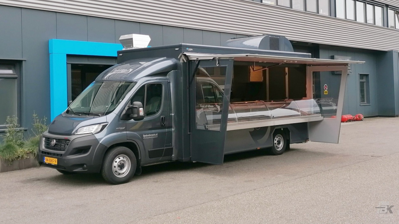 Zijaanzicht van een verkoopwagen voor vis met geopende luifel en zijborden