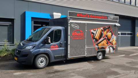 Zijaanzicht van een verkoopwagen voor loempia's met gesloten luifel