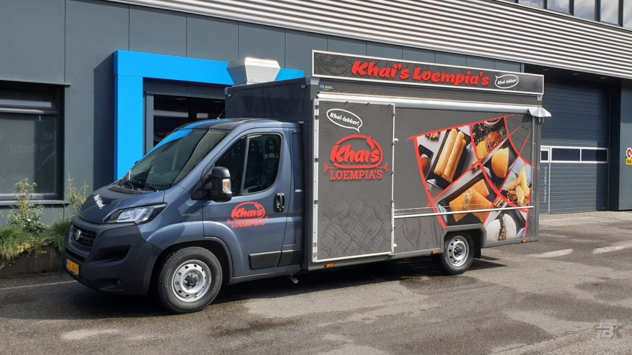 Zijaanzicht van een verkoopwagen voor loempia's met gesloten luifel