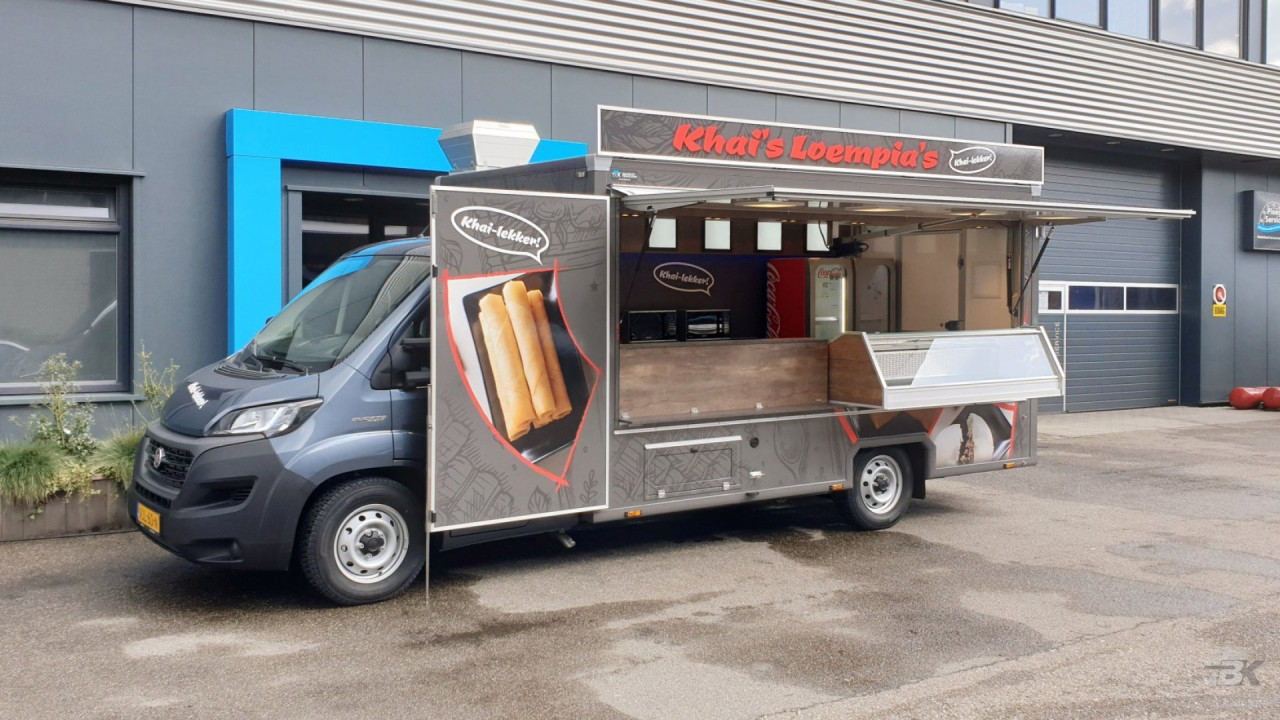 Zijaanzicht van een verkoopwagen voor loempia's met geopende luifel