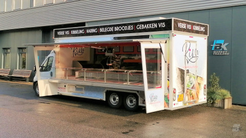 Zijaanzicht van een verkoopwagen voor vis met geopende luifel en zijborden