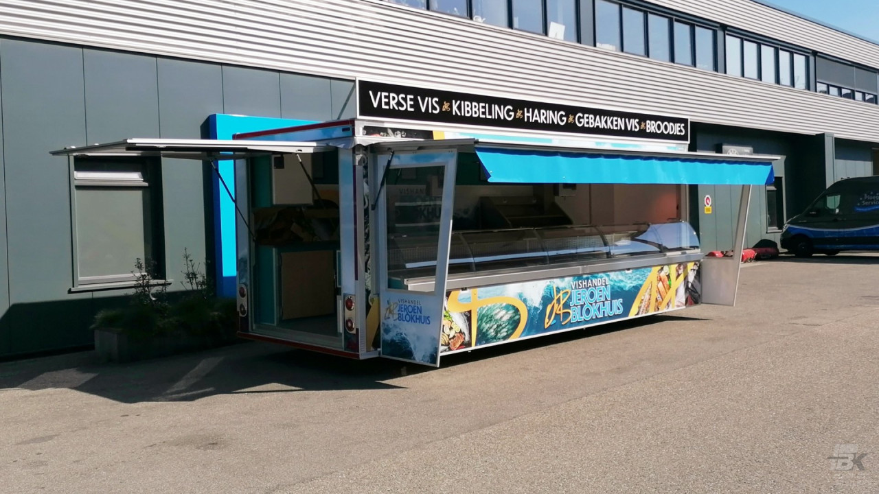 Zijaanzicht van een aanhangwagen voor vis met gesloten luifel en zijborden
