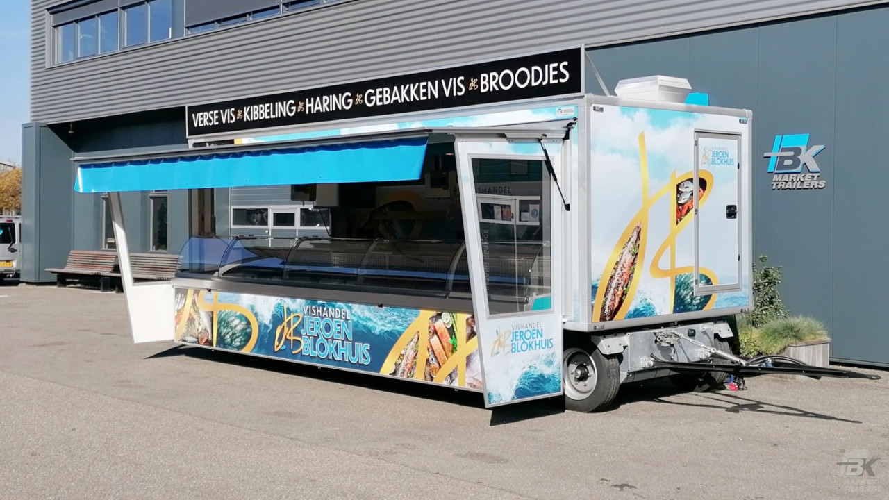 Zijaanzicht van een aanhangwagen voor vis met gesloten luifel en zijborden