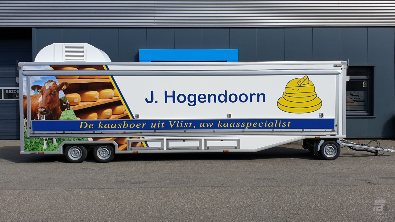 Zijaanzicht van een smalle aanhangwagen voor kaas met gesloten luifel