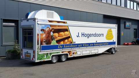 Zijaanzicht van een smalle aanhangwagen voor kaas met gesloten luifel