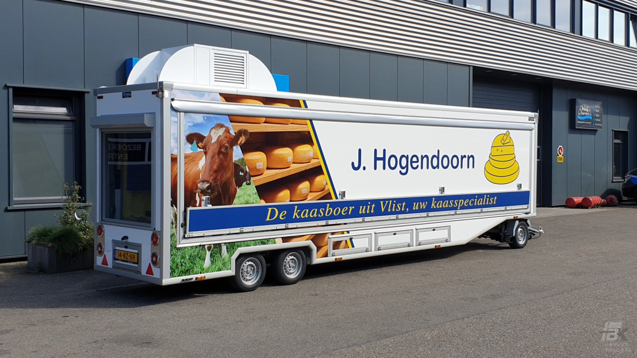 Zijaanzicht van een smalle aanhangwagen voor kaas met gesloten luifel