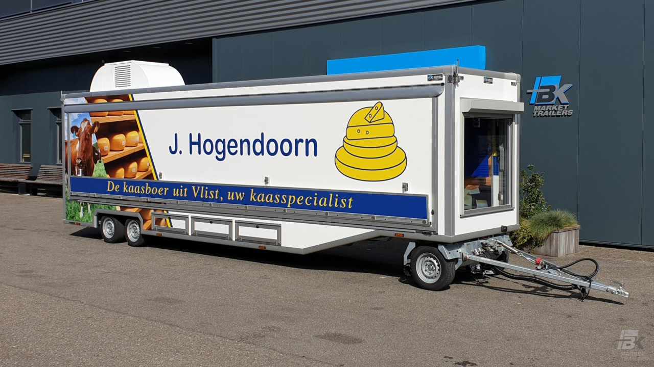 Zijaanzicht van een smalle aanhangwagen voor kaas met gesloten luifel