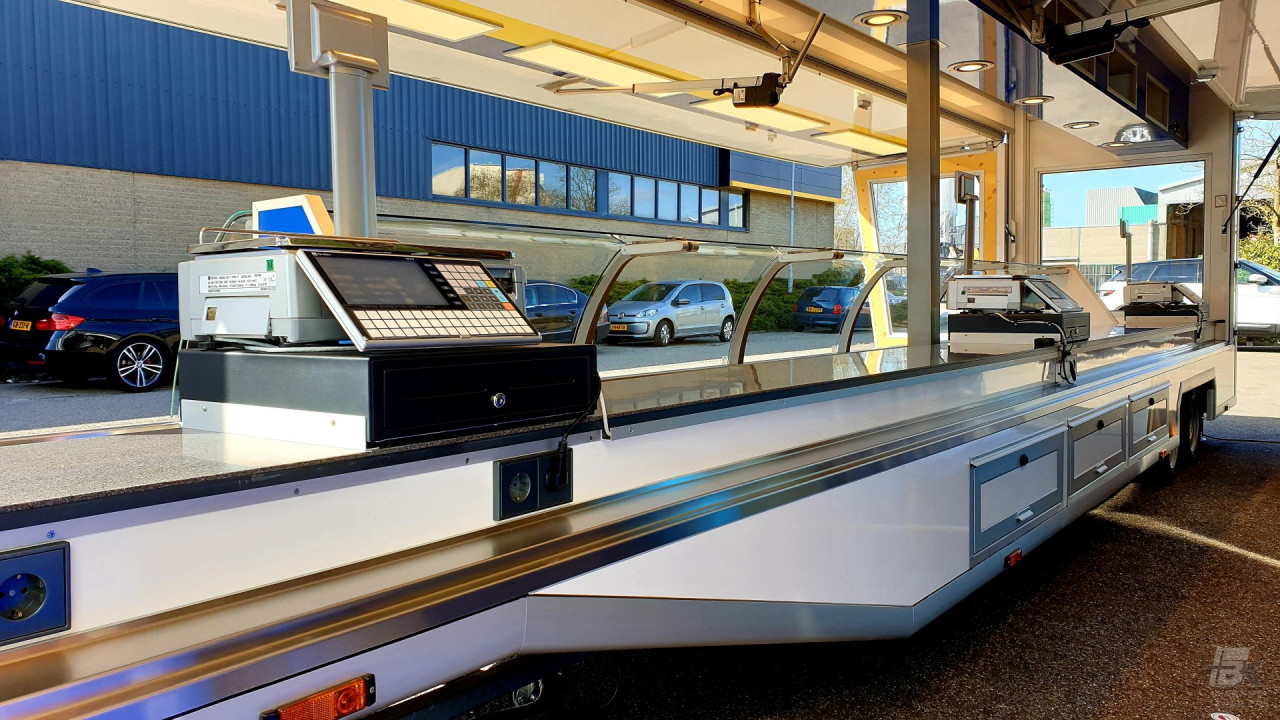 Binnenkant van een smalle aanhangwagen voor kaas met toonbank, vitrine en kassa