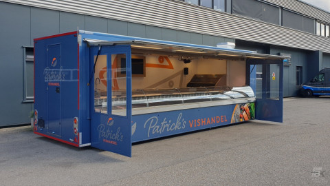 Zijaanzicht van een aanhangwagen voor vis met geopende luifel en zijborden