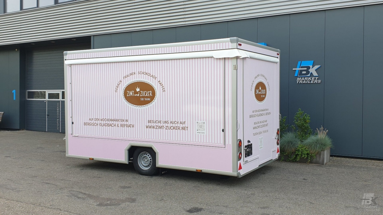 Zijaanzicht van een aanhangwagen voor gebak, chocolade en koffie met gesloten luifel