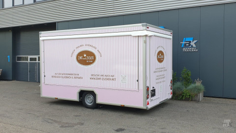 Zijaanzicht van een aanhangwagen voor gebak, chocolade en koffie met gesloten luifel