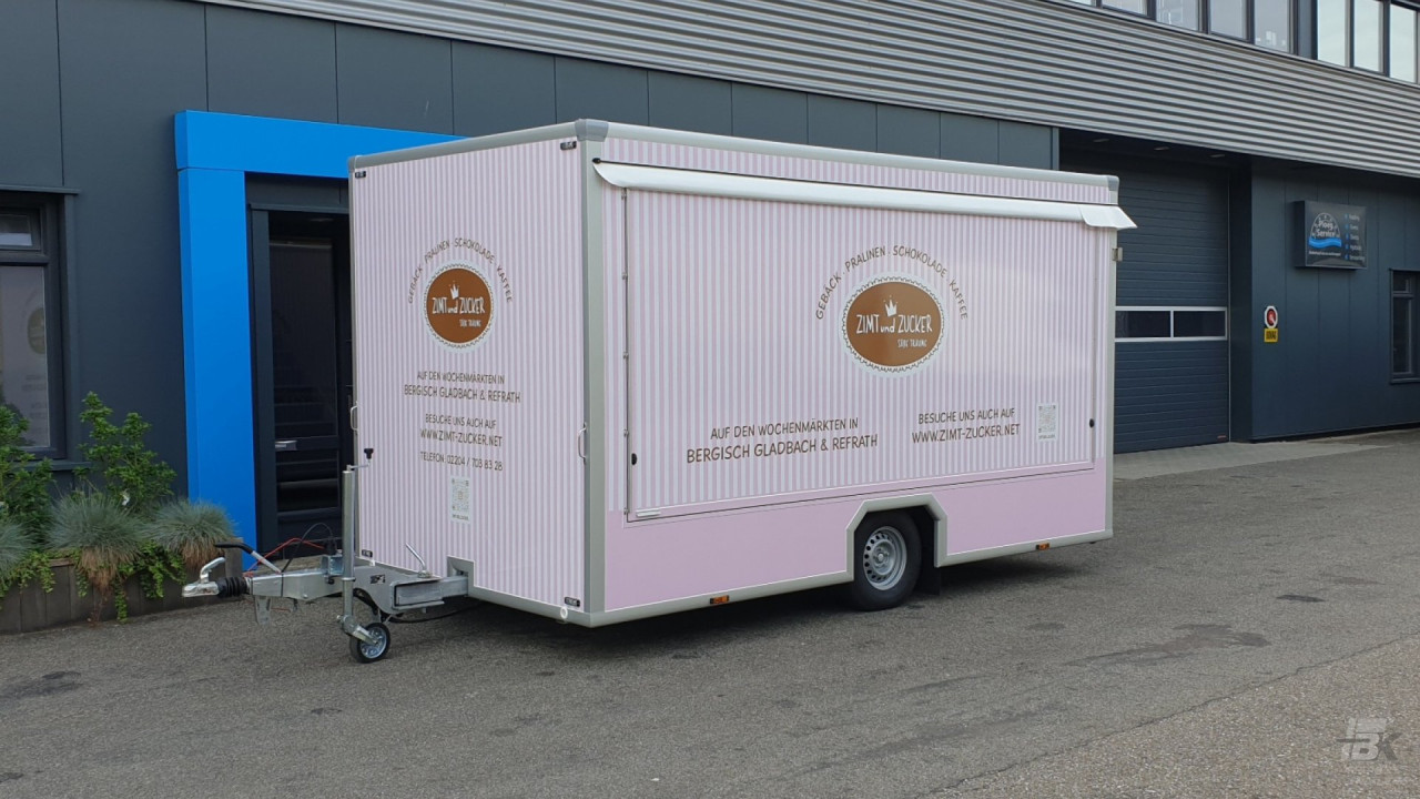 Zijaanzicht van een aanhangwagen voor gebak, chocolade en koffie met gesloten luifel