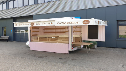 Zijaanzicht van een aanhangwagen voor gebak, chocolade en koffie met geopende luifel