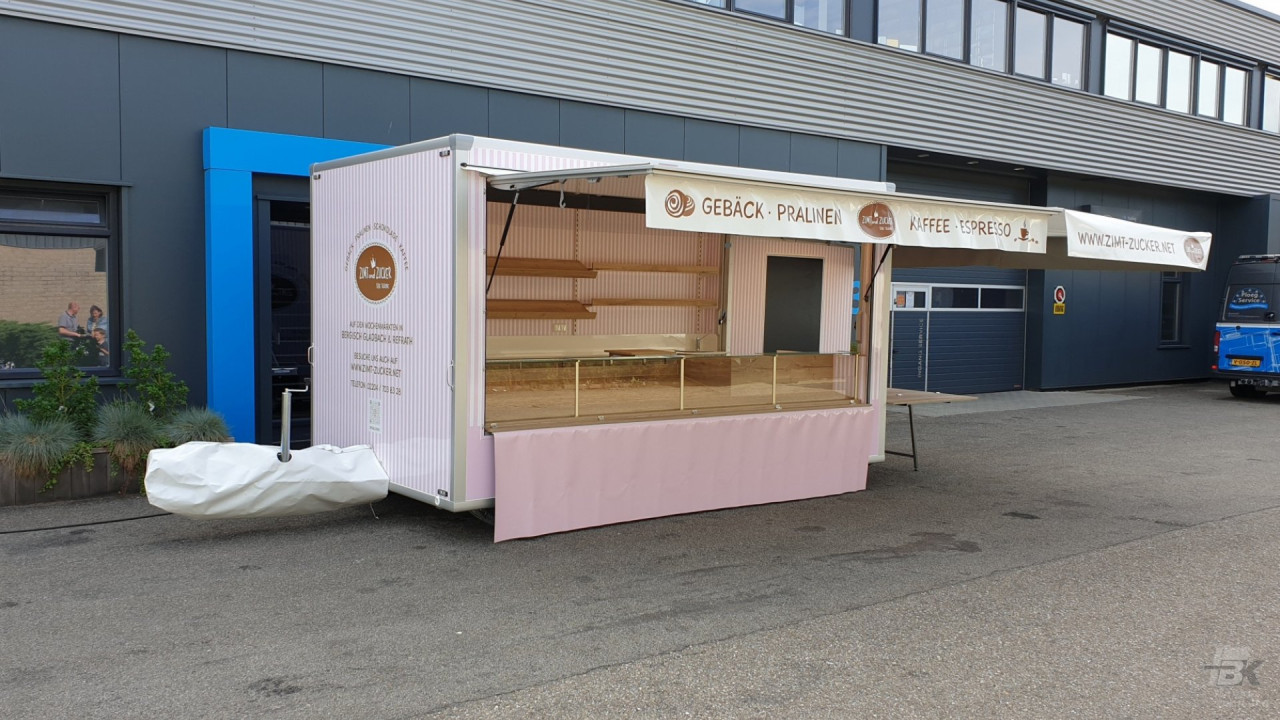 Zijaanzicht van een aanhangwagen voor gebak, chocolade en koffie met geopende luifel