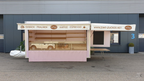 Zijaanzicht van een aanhangwagen voor gebak, chocolade en koffie met geopende luifel