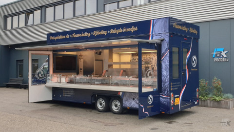 Zijaanzicht van een verkoopwagen voor vis met geopende luifel en zijborden