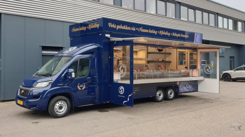 Zijaanzicht van een verkoopwagen voor vis met geopende luifel en zijborden