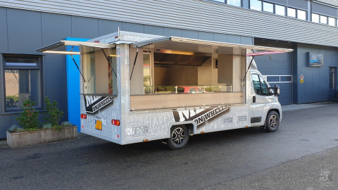 Zijaanzicht van een verkoopwagen voor maaltijden met geopende luifel