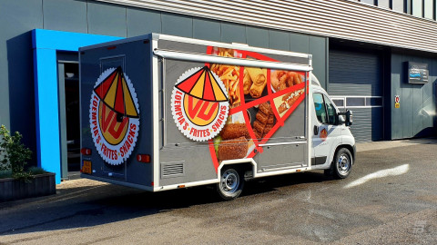 Zijaanzicht van een verkoopwagen voor loempia's, patat en snacks met gesloten luifel